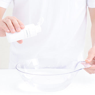 洗面器に35℃くらいのぬるま湯を溜め、ウィッグ用シャンプーをひと回し入れて溶かします。