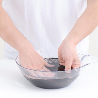 片手でウィッグを持ちながら、毛先から頭頂部までやさしく押し洗いします。