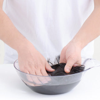 片手でウィッグを持ちながら、毛先から頭頂部までやさしく押し洗いします。